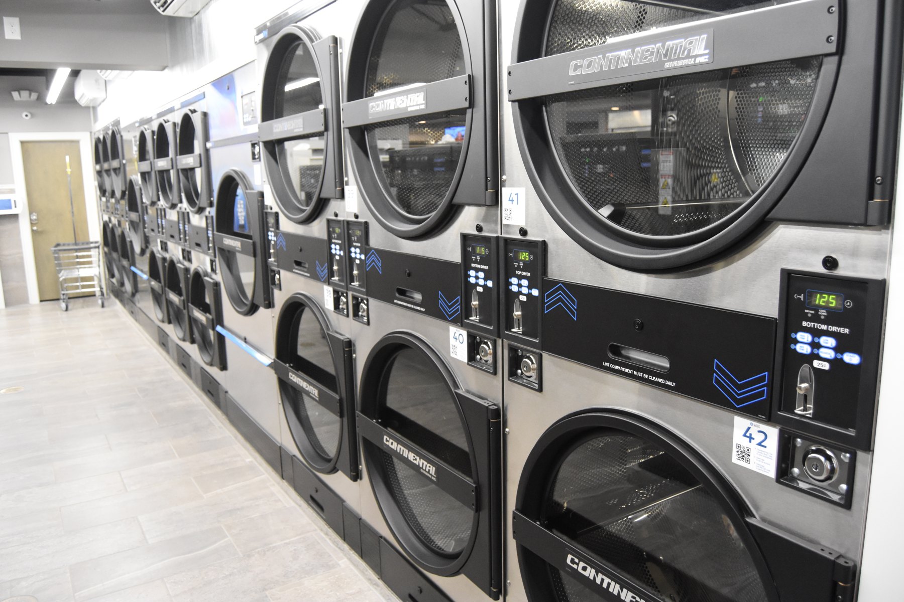 The dryer wall and bright tiled floor inside Express Laundry Center